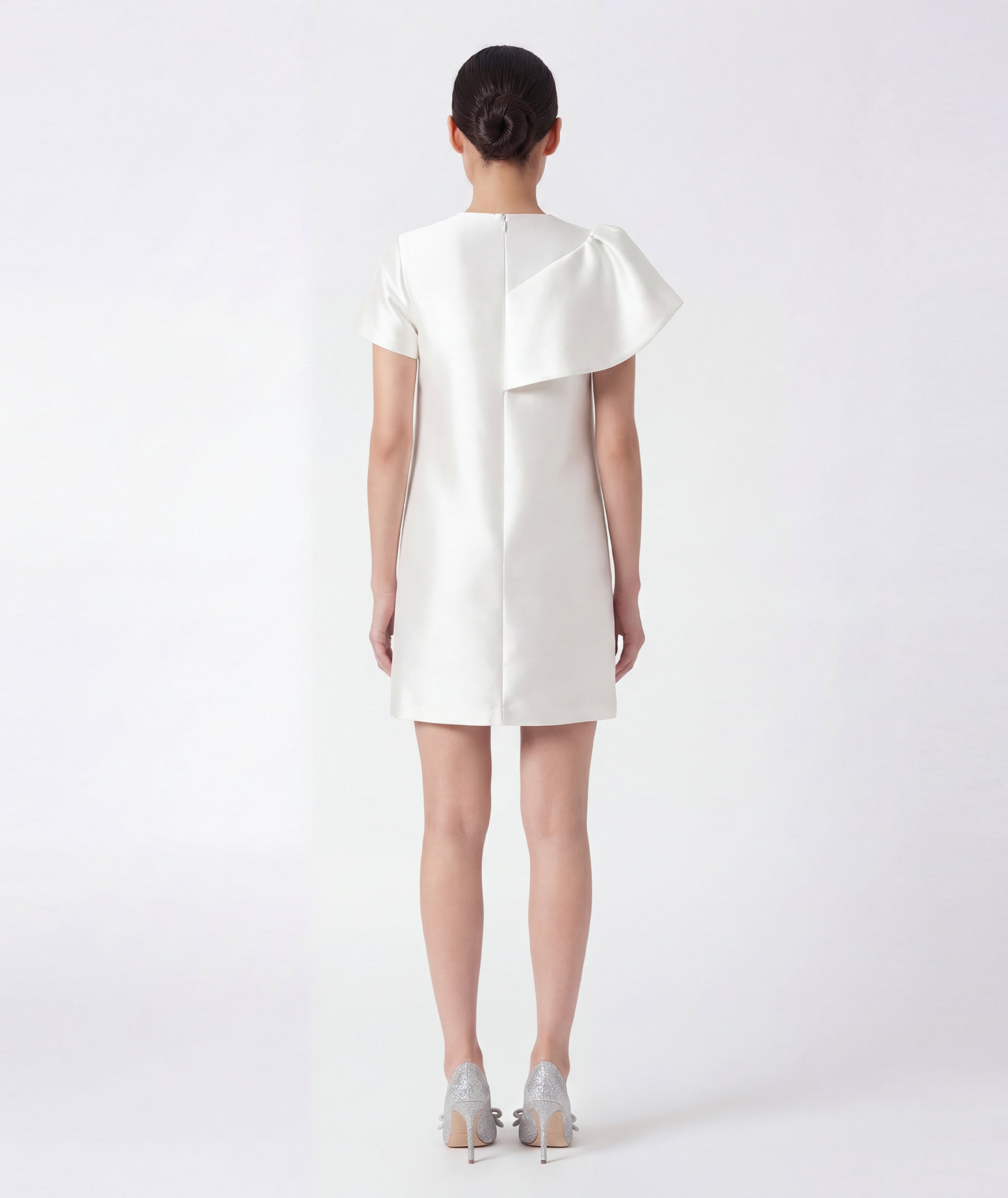 Woman wearing a white dress with a ruffled collar on a white background