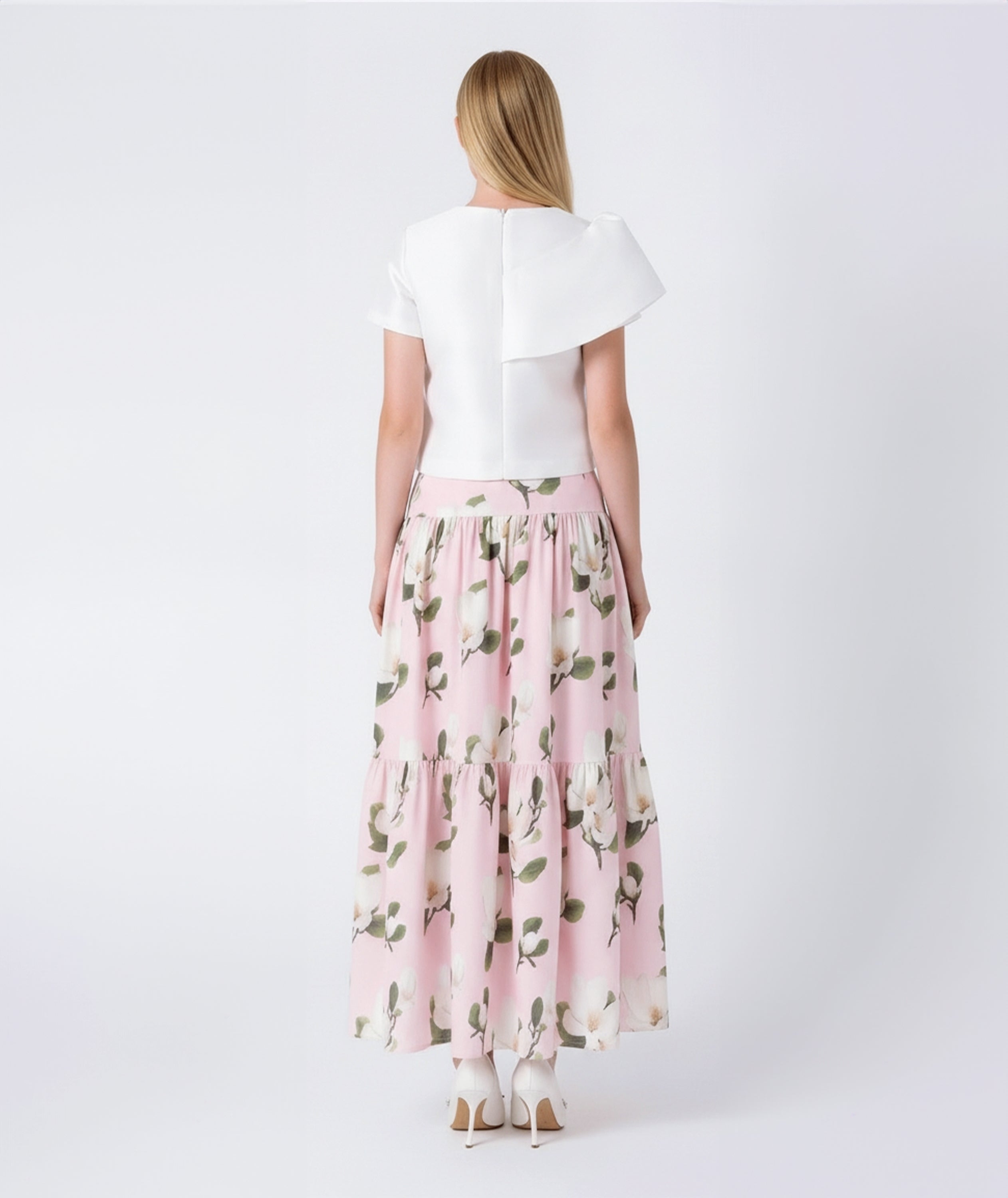 Woman wearing a white top and pink floral skirt on a white background