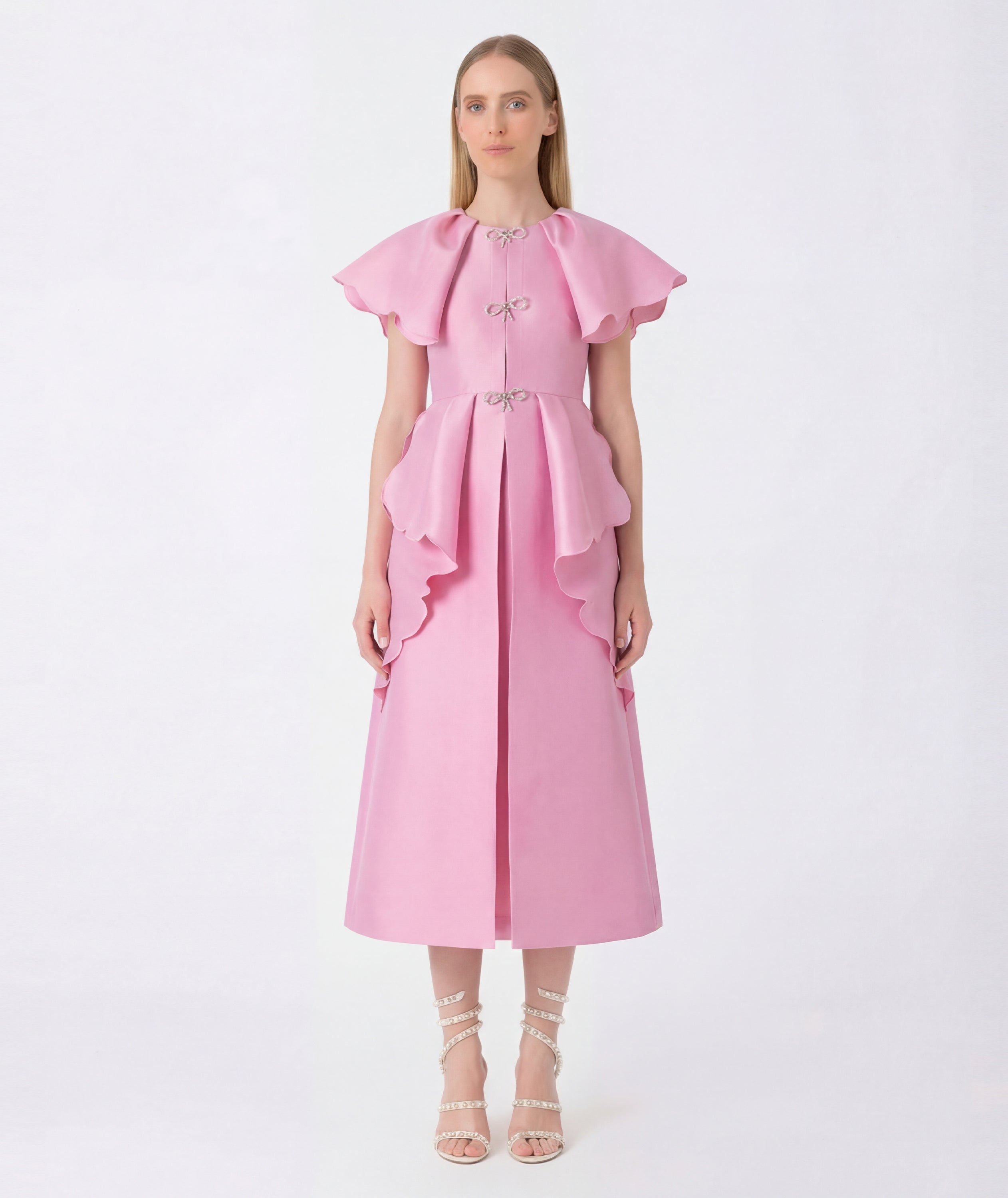 Woman wearing a pink dress with ruffled sleeves on a white background
