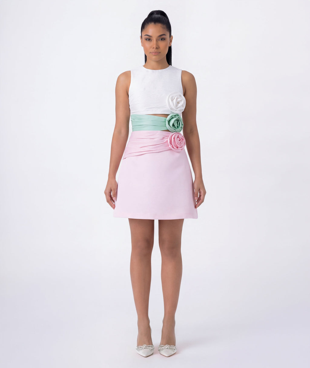 Woman wearing a white top and pink skirt with floral details on a white background
