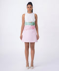 Woman wearing a white top and pink skirt with floral details on a white background