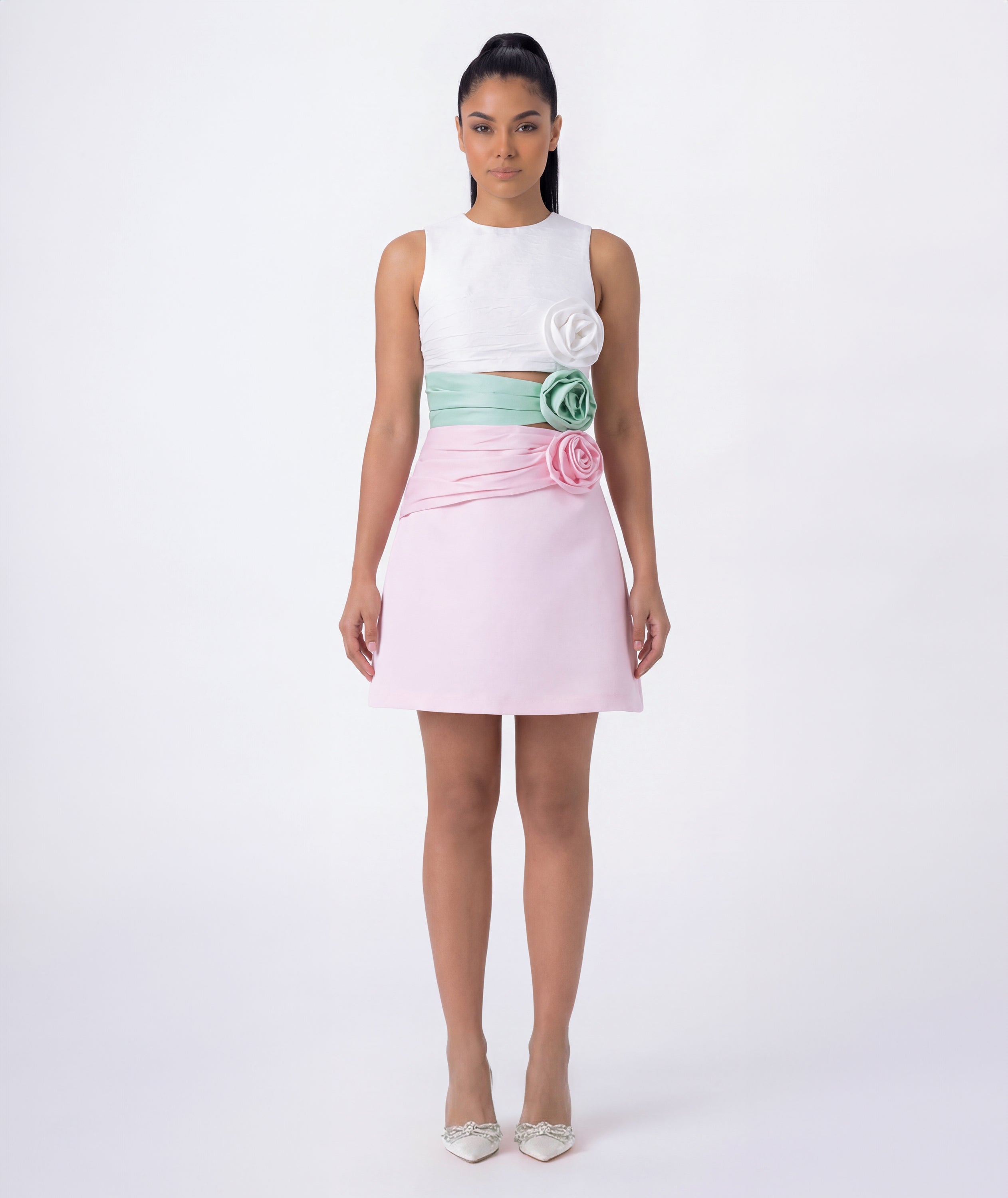 Woman wearing a white top and pink skirt with floral details on a white background