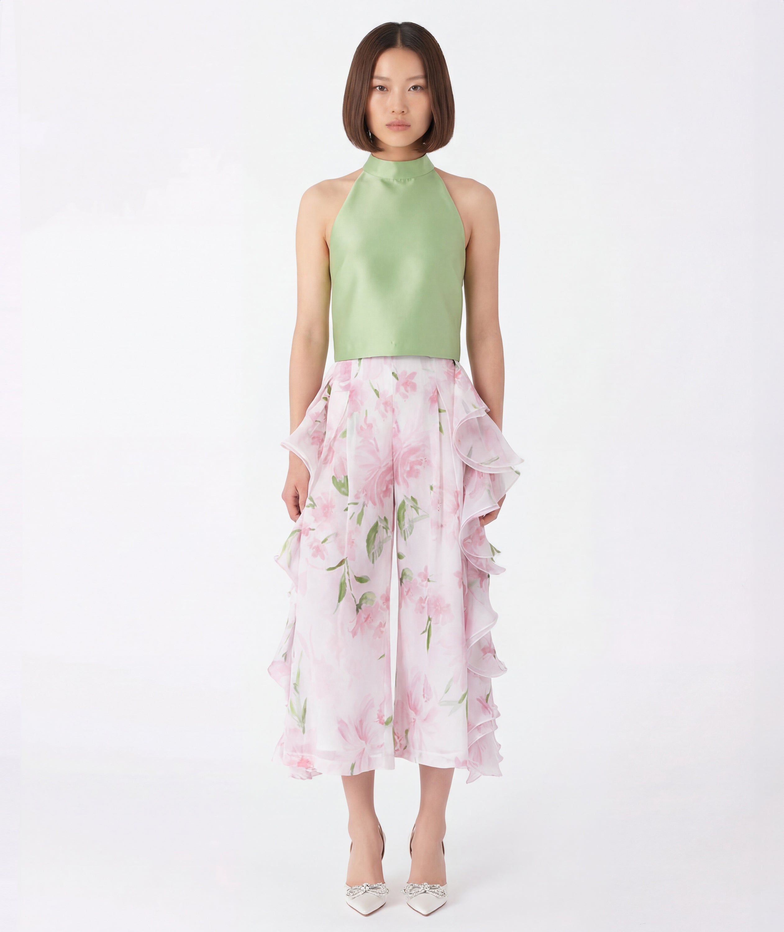 Woman wearing a light green top and pink floral skirt on a white background