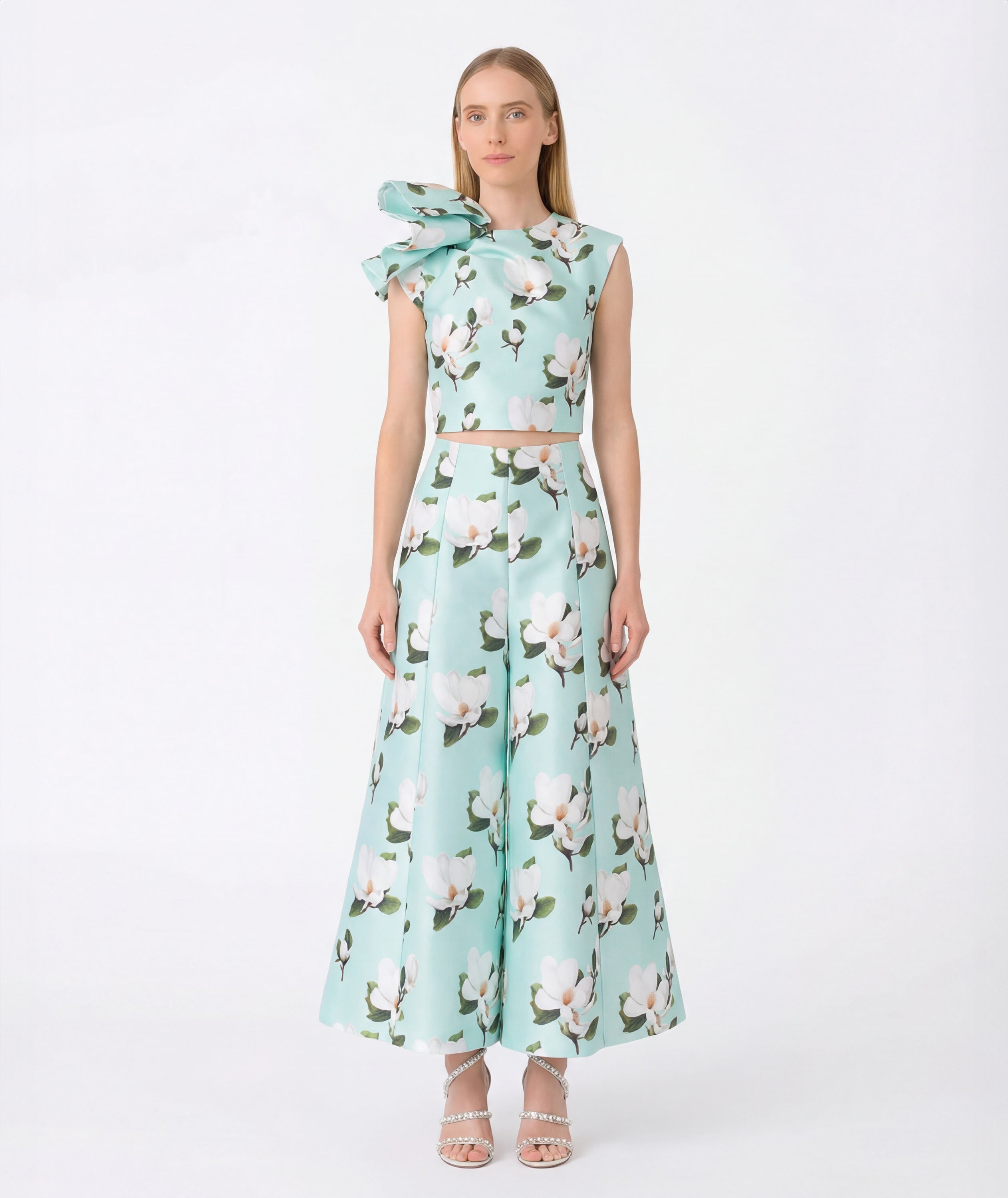 Women’s mint green floral two-piece outfit with a sleeveless statement bow top and flowing wide-leg floral pants, styled for garden weddings, spring events, resort occasions, and elegant daytime celebrations, available in sizes XS to XL.